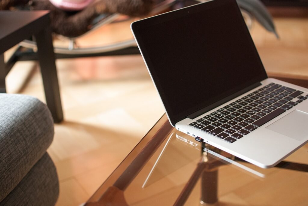 A laptop on a glass desk, the kind of machine whose price rose because AI is consuming the memory supply