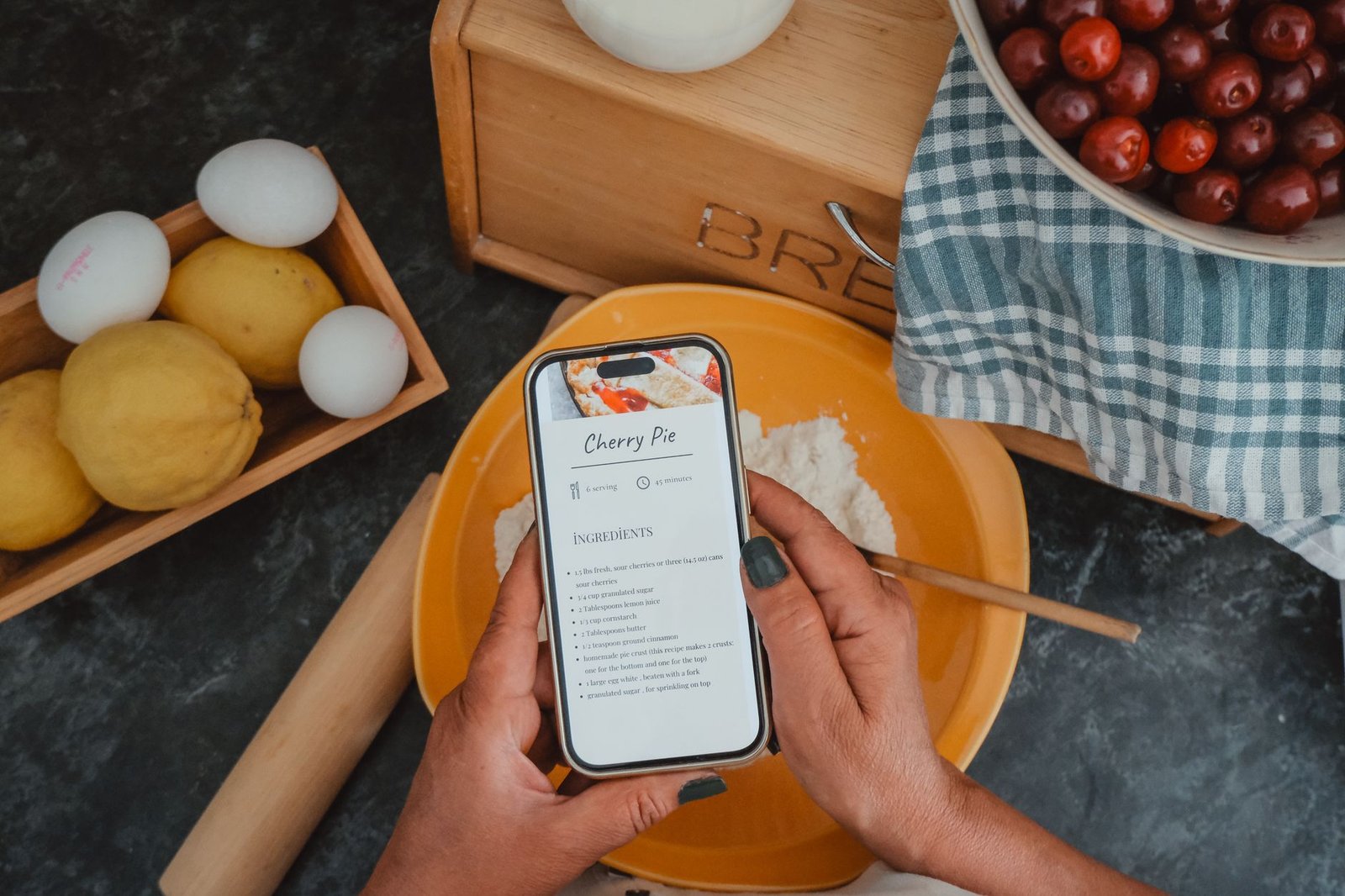 Hands holding a phone with a recipe open while cooking, a perfect hands-free GPT-Live moment
