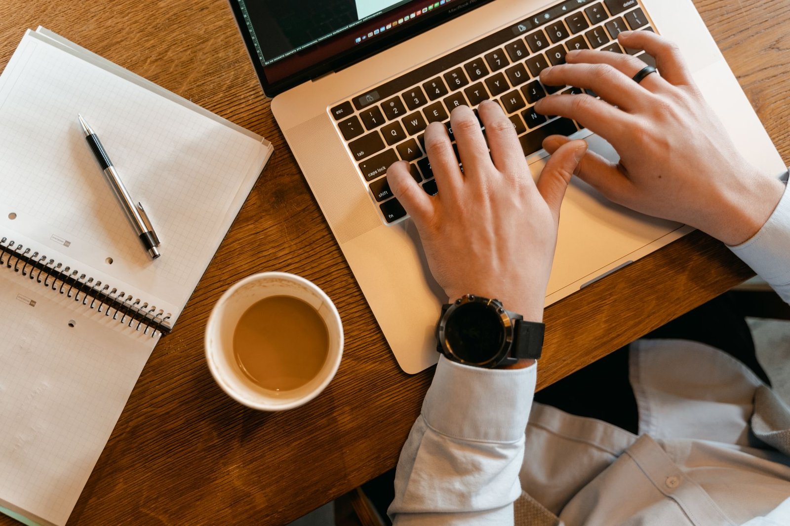 Hands typing on a laptop next to a notebook, setting up a study plan