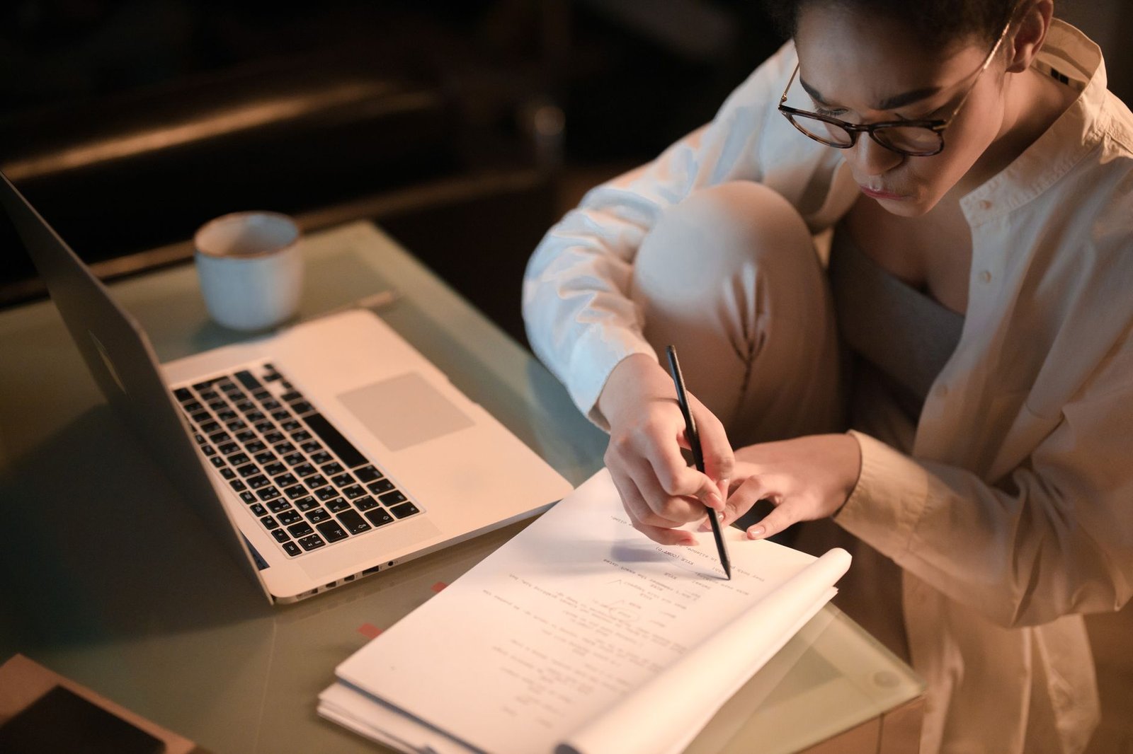 Adult taking notes at night while studying at home for a certification
