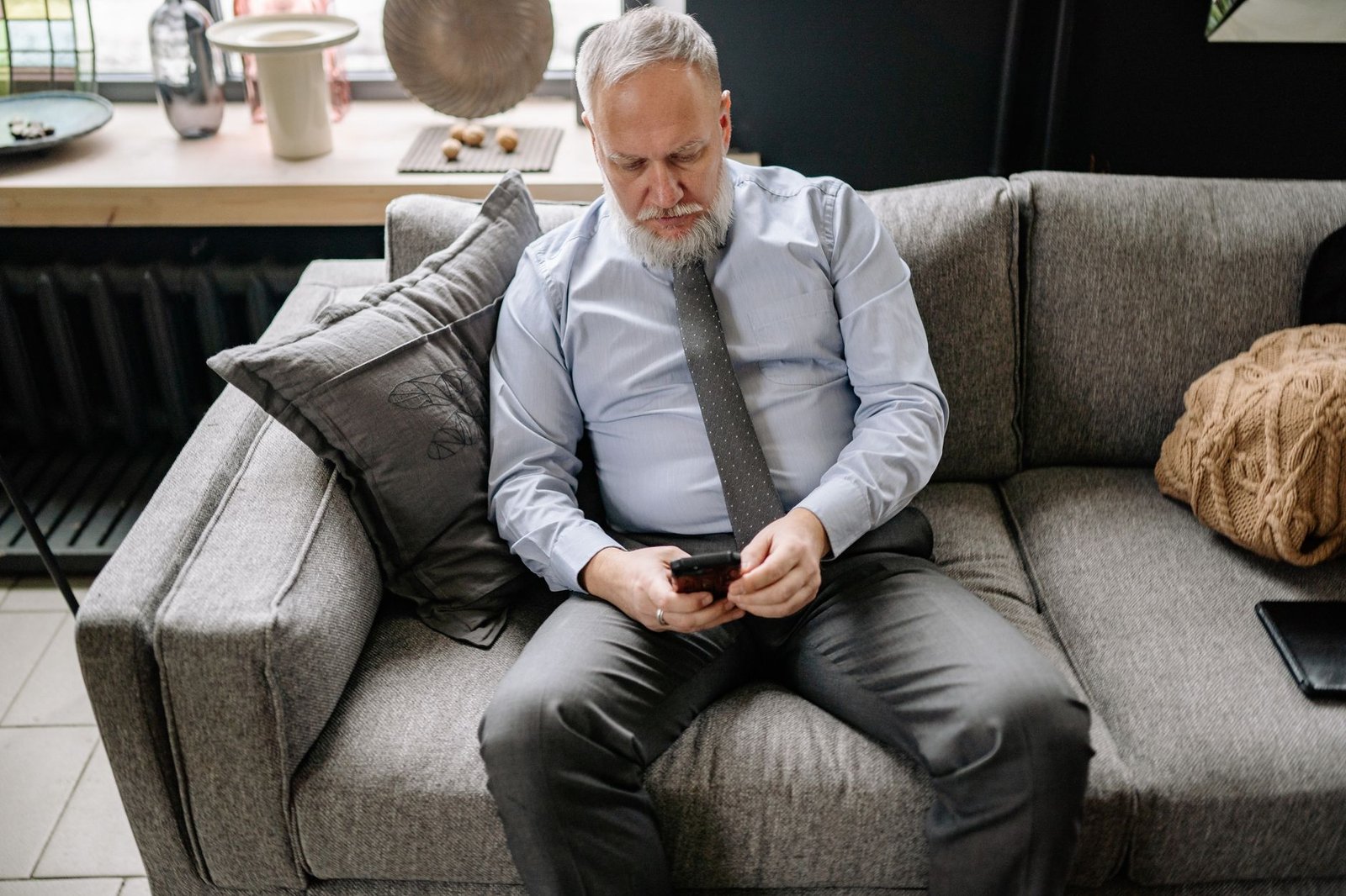 A man checking alerts on his phone from the couch, with fewer junk notifications thanks to Ring AI Unusual Event Alert