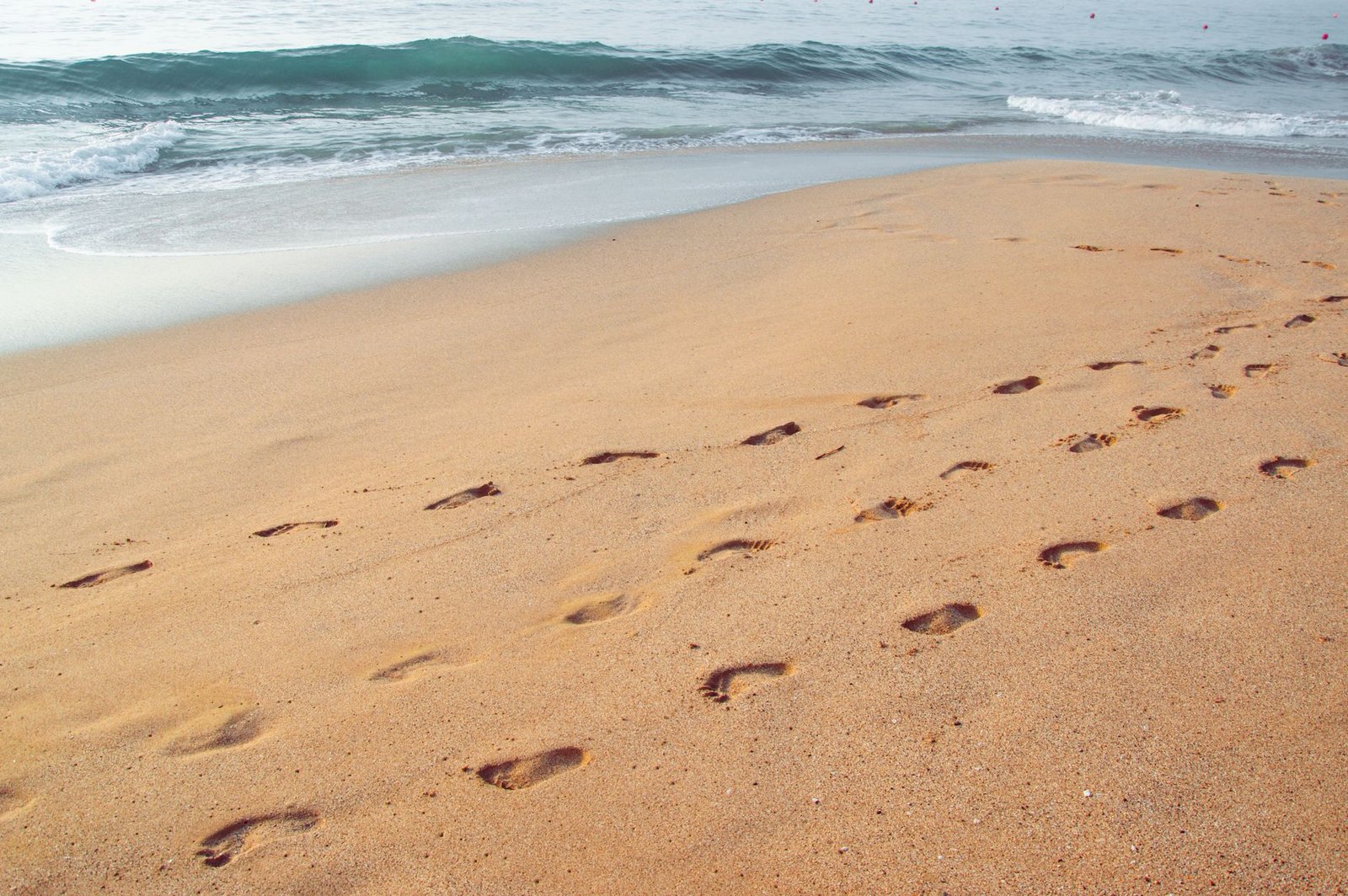 Footprints leading across a beach, a stand-in for the usage signals ChatGPT for Teens reads to guess a user is under 18
