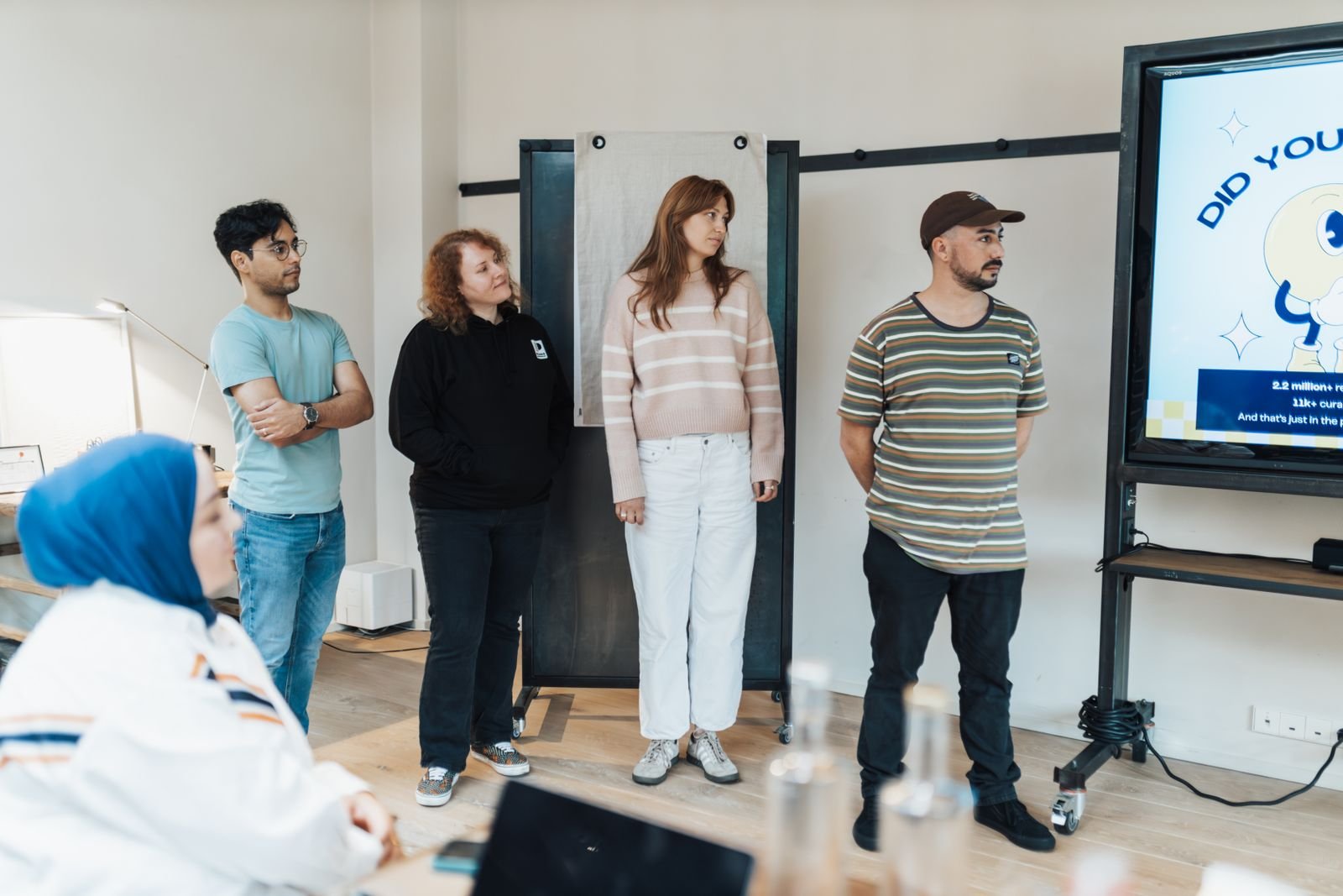 A group of adults in a bright office watching a slide presentation