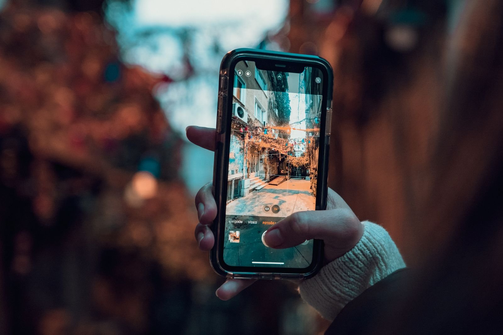 A hand holding a smartphone up to a city street, the way you would to start Search Live in the Google app