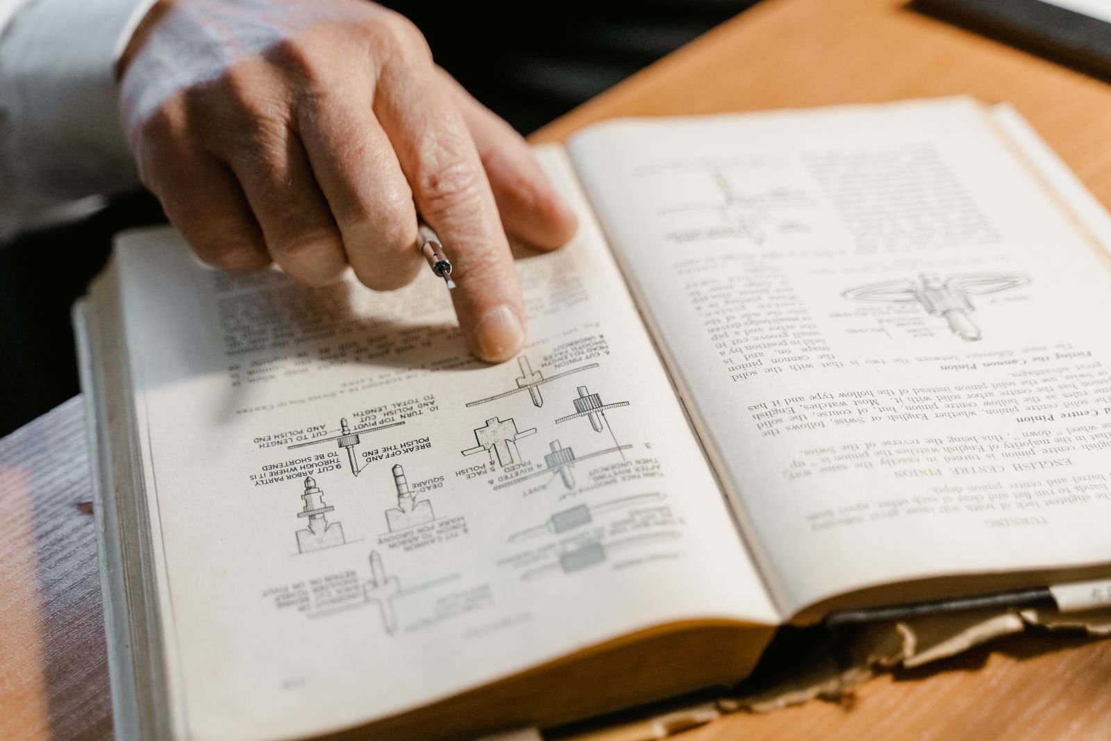 A hand pointing at diagrams in an old engineering manual, the kind of dense technical page a general reader struggles with